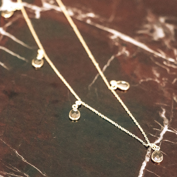 Our Smokey Quartz charm necklace features five stones delicately attached to a fine gold plated chain creating this easy to wear and lightweight necklace