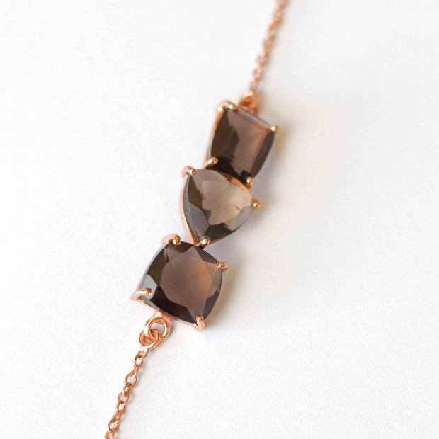 Three Smokey Quartz stones are each cut in unique shapes and placed together to create a unique balanced bar style bracelet. Set on a dainty rose gold-plated adjustable chain