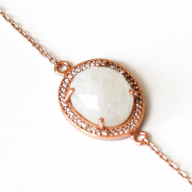 A beautiful Rainbow Moonstone surrounded by a pave halo of cubic zirconias set on a dainty adjustable 14 carat rose gold plated chain