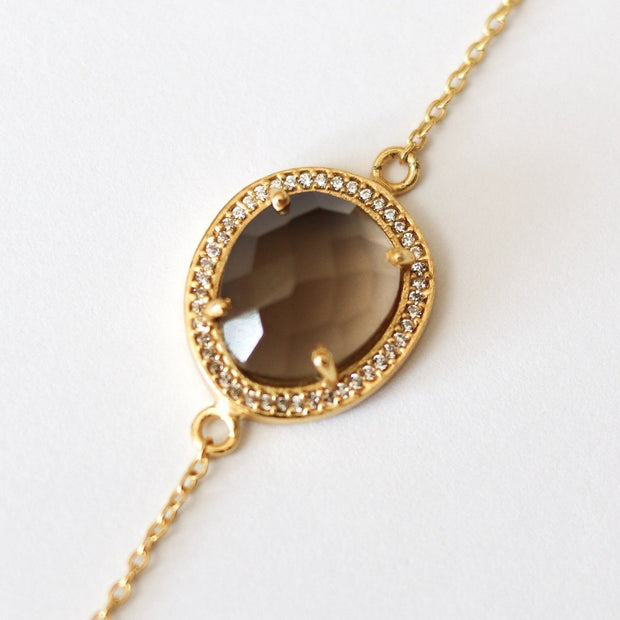 Our halo bracelet features a rose-cut Smokey Quartz stone set within a halo of cubic zirconias on a dainty adjustable gold plated chain