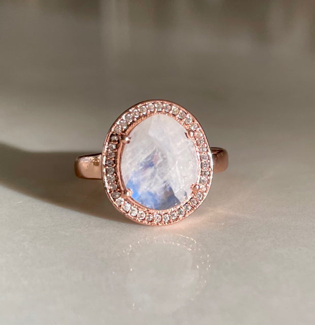 A beautiful Rainbow Moonstone rose-cut stone is surrounded by a halo of pave set cubic zirconias
